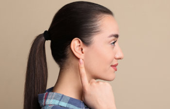 young-woman-pointing at her ear on beige background
