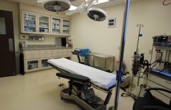 An empty modern operating room with surgical equipment and an operating table.