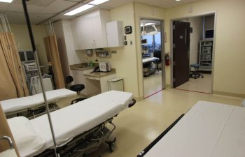 An empty hospital room with two beds and medical equipment.