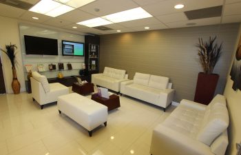 Modern office waiting room with white couches, a coffee table, and decorative elements.