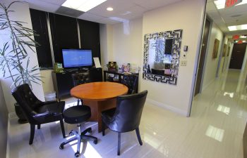 Modern office waiting area with seating, a round table, and a beverage station.