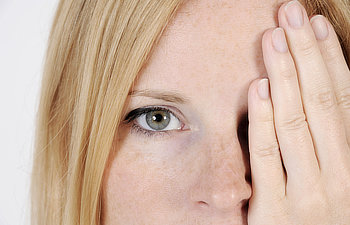woman with sun spotted face she is covering one of her eyes with her hand